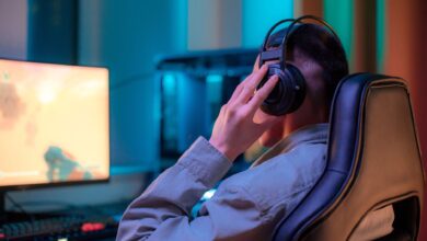 A man in headphones gaming on a computer at a stylish desk setup.