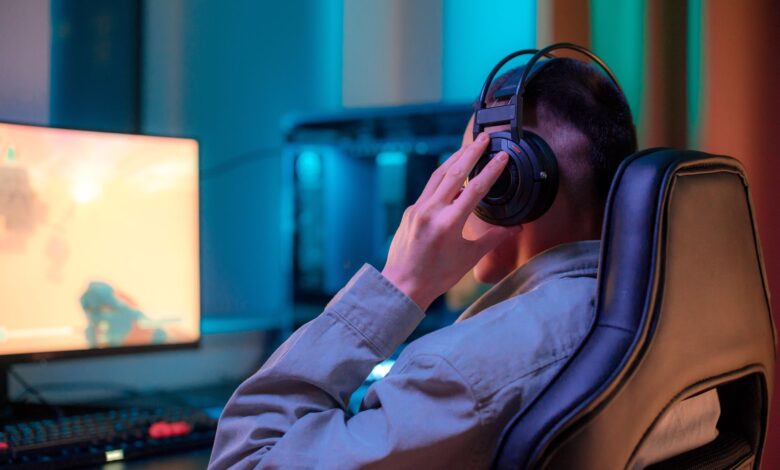 A man in headphones gaming on a computer at a stylish desk setup.
