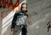 A woman posing in a futuristic outfit with graffiti in the background.