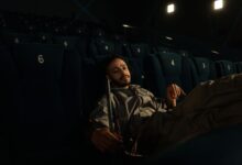 Man in uniform resting on cinema seats during a quiet moment at work.