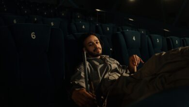 Man in uniform resting on cinema seats during a quiet moment at work.