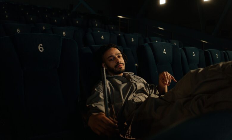Man in uniform resting on cinema seats during a quiet moment at work.