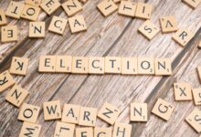 Wooden letter tiles form the word 'election' on a textured wooden surface, symbolizing voting.