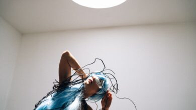 A futuristic woman with blue hair and wires in a cyberpunk style indoors.