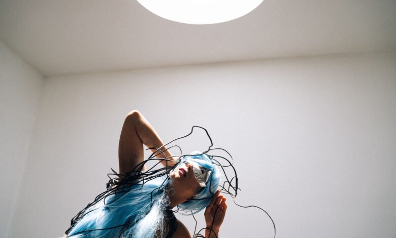 A futuristic woman with blue hair and wires in a cyberpunk style indoors.