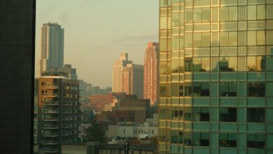View of New York City's skyline at dawn with reflections on modern buildings.