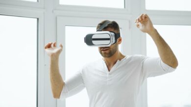 Young man immersed in virtual reality experience using VR headset in a bright room.