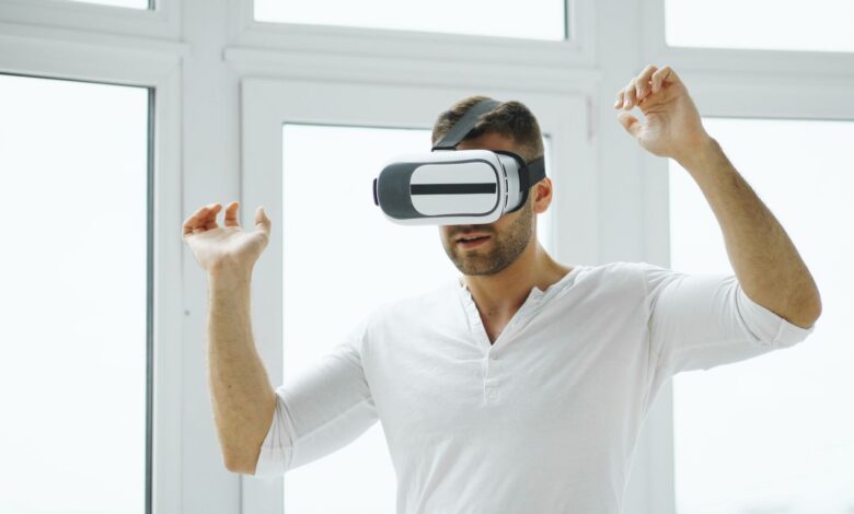 Young man immersed in virtual reality experience using VR headset in a bright room.