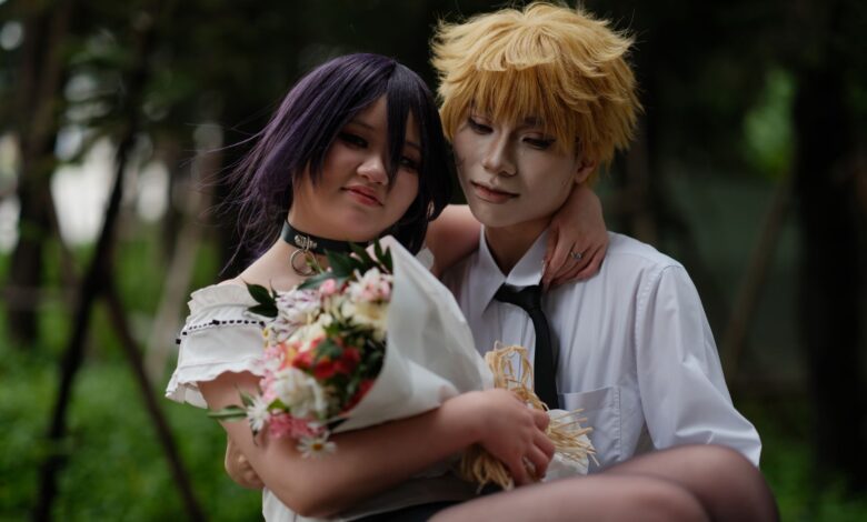 A couple in anime-style cosplay poses outdoors, with a bouquet and a warm embrace.