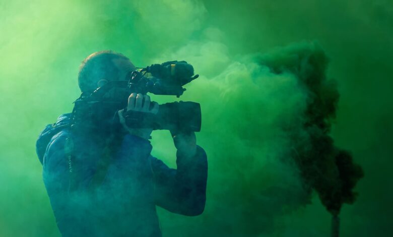A professional cameraman captures footage surrounded by striking green smoke, highlighting filmmaking elements.