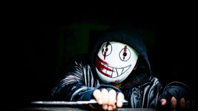 A mysterious figure wearing a creepy smiling mask in a dark setting, creating an eerie atmosphere.
