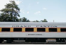 Side view of a vintage Grand Canyon Railway passenger car under a clear sky.