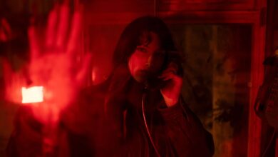 A woman in a telephone booth, surrounded by dramatic red lighting.