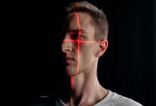 Studio portrait of a man with a laser grid pattern for facial recognition on a black background.