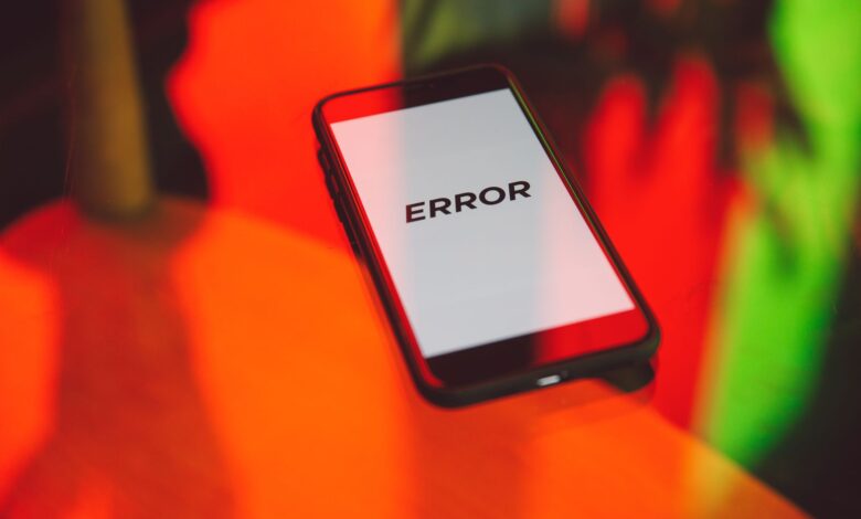 A smartphone displaying an 'ERROR' message surrounded by vibrant red and green reflections indoors.