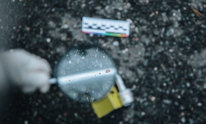 Close-up of evidence analysis at a crime scene with a magnifying glass.