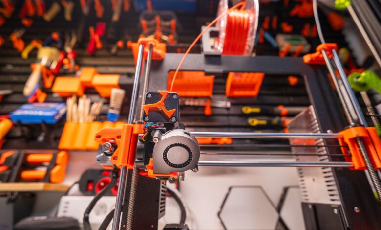 Detailed view of a 3D printer with filament and tools in a workshop setting.