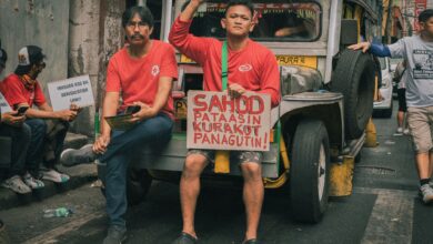 Men protesting in Manila, demanding higher wages and accountability, sitting on a jeepney in the street.