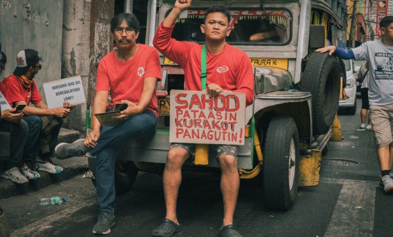 Men protesting in Manila, demanding higher wages and accountability, sitting on a jeepney in the street.