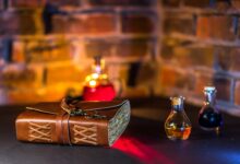A spell book and potions in glass bottles with a brick wall backdrop.