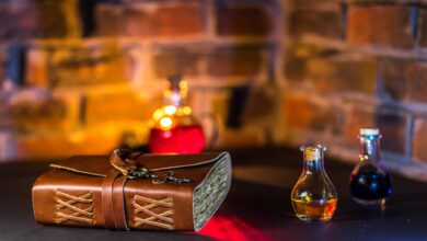 A spell book and potions in glass bottles with a brick wall backdrop.