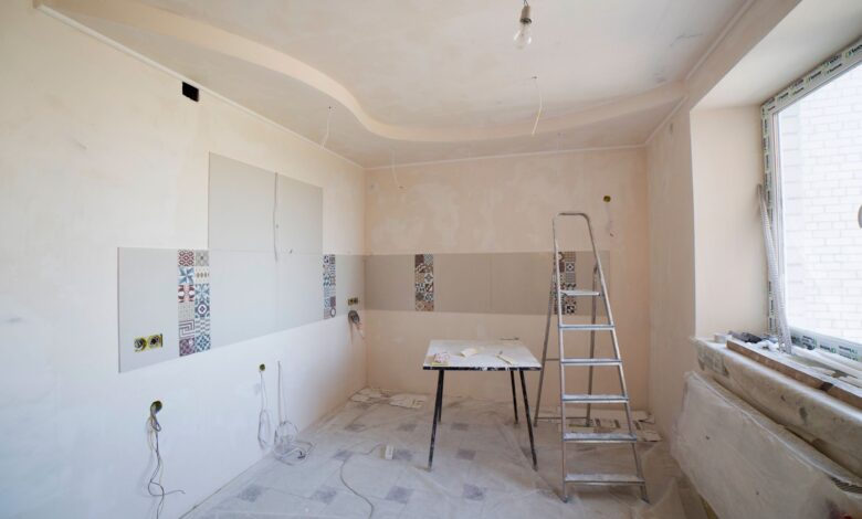 Spacious kitchen under renovation with ladder and tools, showcasing a fresh new design.