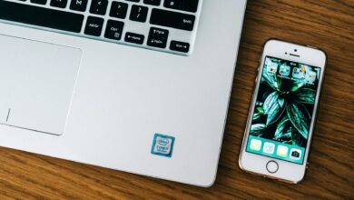 Close-up of a laptop and smartphone on a wooden desk in an office setting.