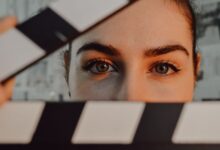 Intriguing close-up of a person's eyes behind a movie clapperboard, symbolizing filmmaking artistry.