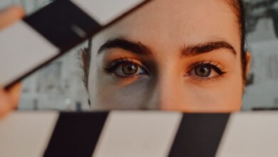 Intriguing close-up of a person's eyes behind a movie clapperboard, symbolizing filmmaking artistry.