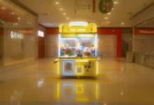 Brightly lit claw machine in a deserted shopping mall with plush toys inside.