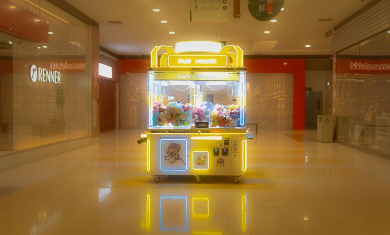 Brightly lit claw machine in a deserted shopping mall with plush toys inside.