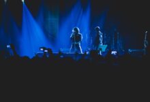 A lively concert scene with vivid lighting, featuring a singer and band on stage.
