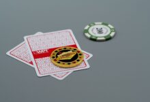 Two playing cards and poker chips, including a Las Vegas chip, on a grey background. Ideal for casino or gambling themes.