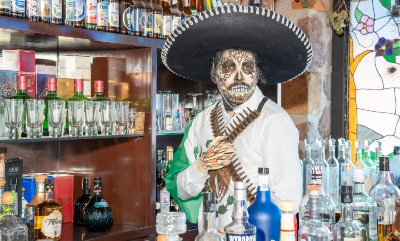 Colorful Day of the Dead themed bar setting in Ciudad de México with traditional attire.