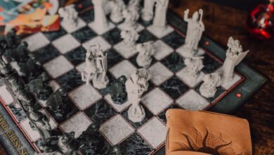 Close-up of a detailed wizard-themed chess set on a wooden table with game card.