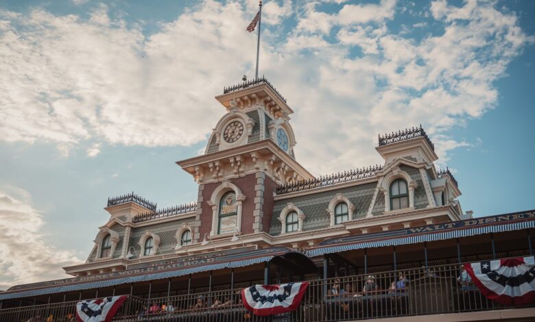 Iconic entrance to Walt Disney World Railroad at Magic Kingdom, Orlando, Florida, with vintage architecture and American flags.
