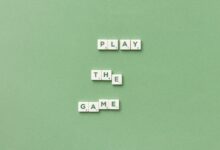 Scrabble letter tiles spelling 'Play the Game' on light green background.