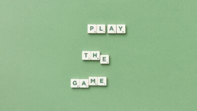 Scrabble letter tiles spelling 'Play the Game' on light green background.