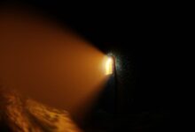 Atmospheric stone corridor with a glowing light beam creating a dramatic shadow.