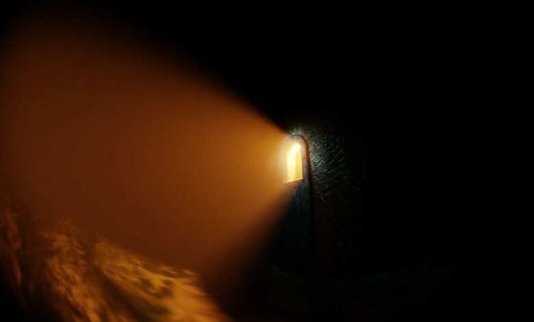 Atmospheric stone corridor with a glowing light beam creating a dramatic shadow.