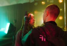 A man with a prosthetic hand gently touches a woman's face in a cyberpunk setting.