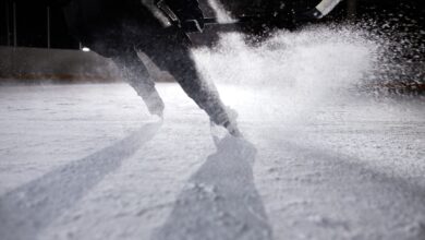 High-energy ice hockey player in action, creating an ice spray during a game on a frozen rink.
