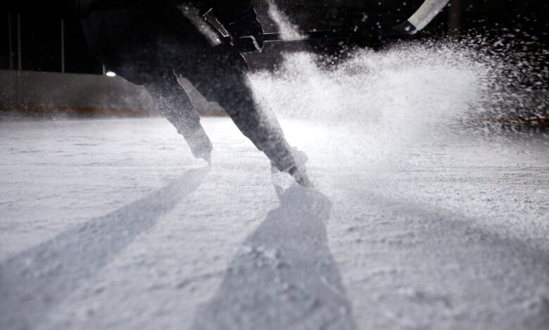 High-energy ice hockey player in action, creating an ice spray during a game on a frozen rink.