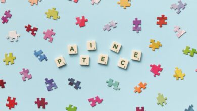 Scattered jigsaw puzzle pieces and Scrabble letters spelling 'PATIECE' on a light blue background.