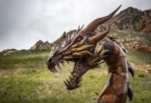 Impressive steel dragon sculpture set against a rugged and picturesque landscape.