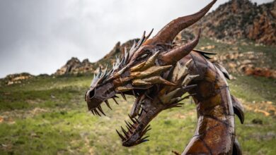 Impressive steel dragon sculpture set against a rugged and picturesque landscape.