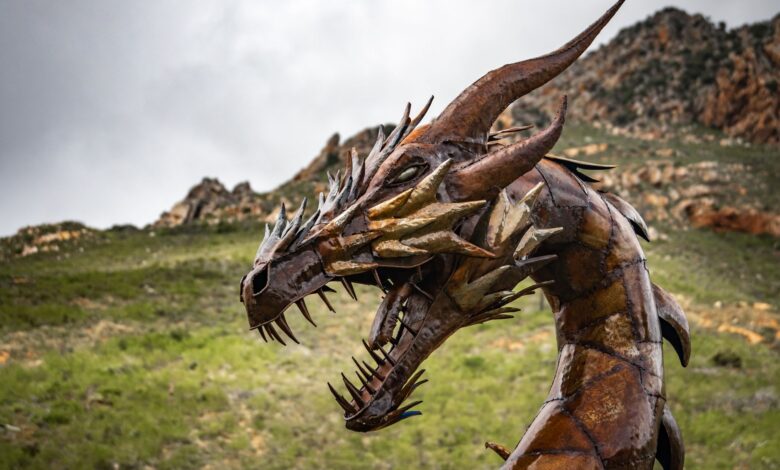 Impressive steel dragon sculpture set against a rugged and picturesque landscape.
