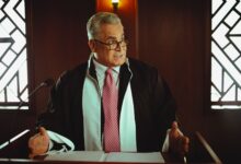 Senior male lawyer presenting a case in a Baghdad courtroom, wearing a classic black robe.