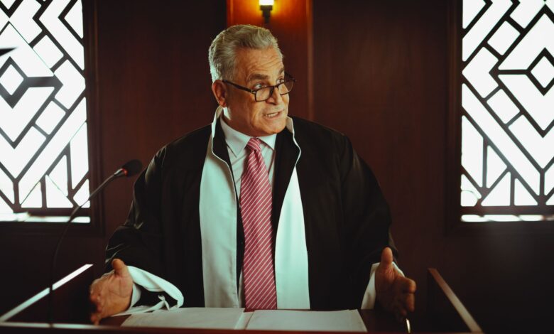 Senior male lawyer presenting a case in a Baghdad courtroom, wearing a classic black robe.