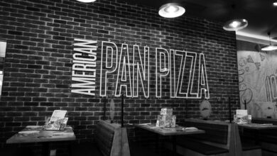 Black and white image of an American pan pizza restaurant with stylish brick wall decor.